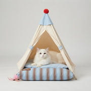 White cat lying on the cushioned floor of a beige indoor pet teepee