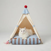 White cat resting inside a beige pet tent bed with blue striped cushion